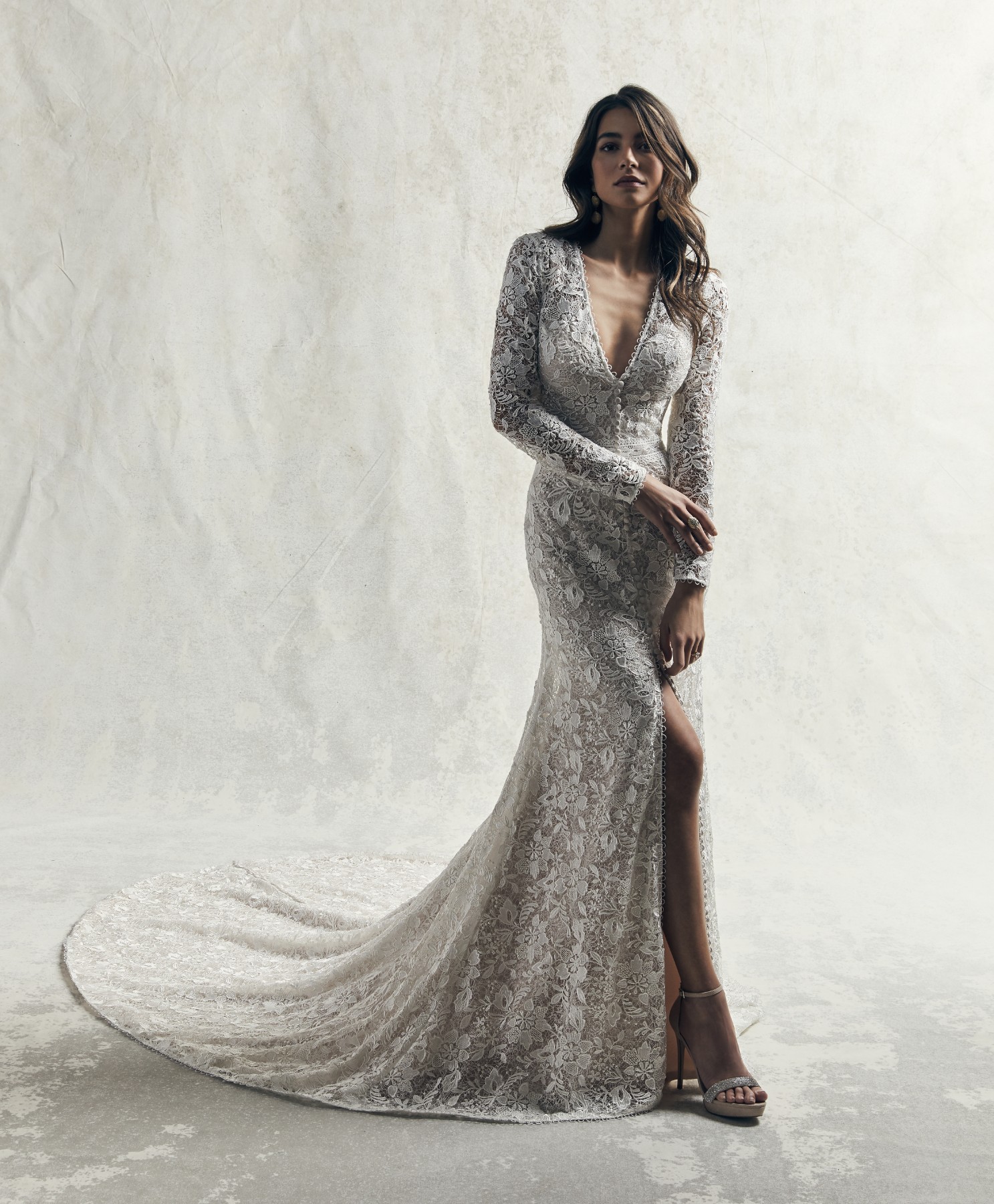 Este maravilhoso vestido de noiva com mangas compridas é confecionado com pormenores de renda sobre tule num vestido justo.