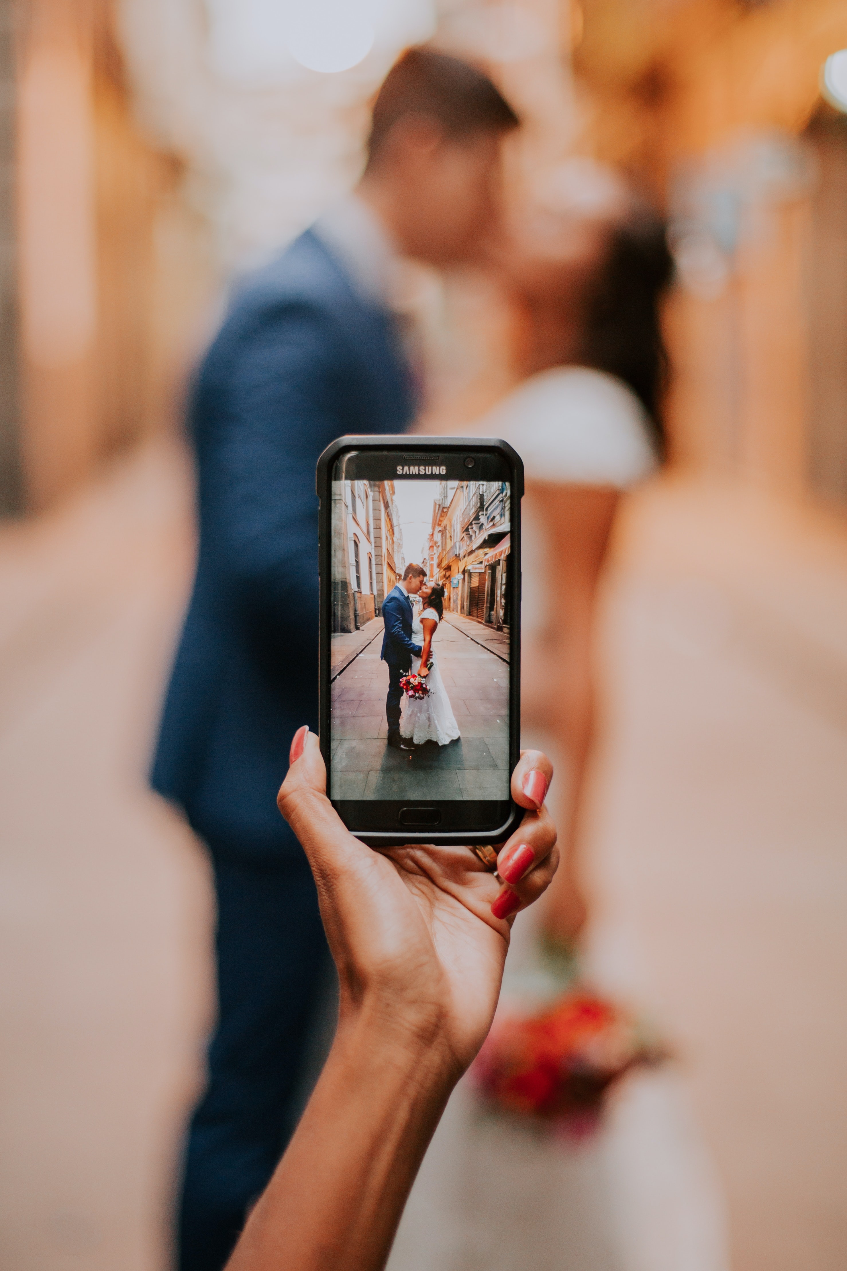 pessoa a pegar num smartphone fotografar noivos
